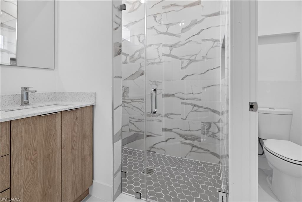 Glass-enclosed shower with white marble-look subway tile surround and gray hexagonal tile flooring
