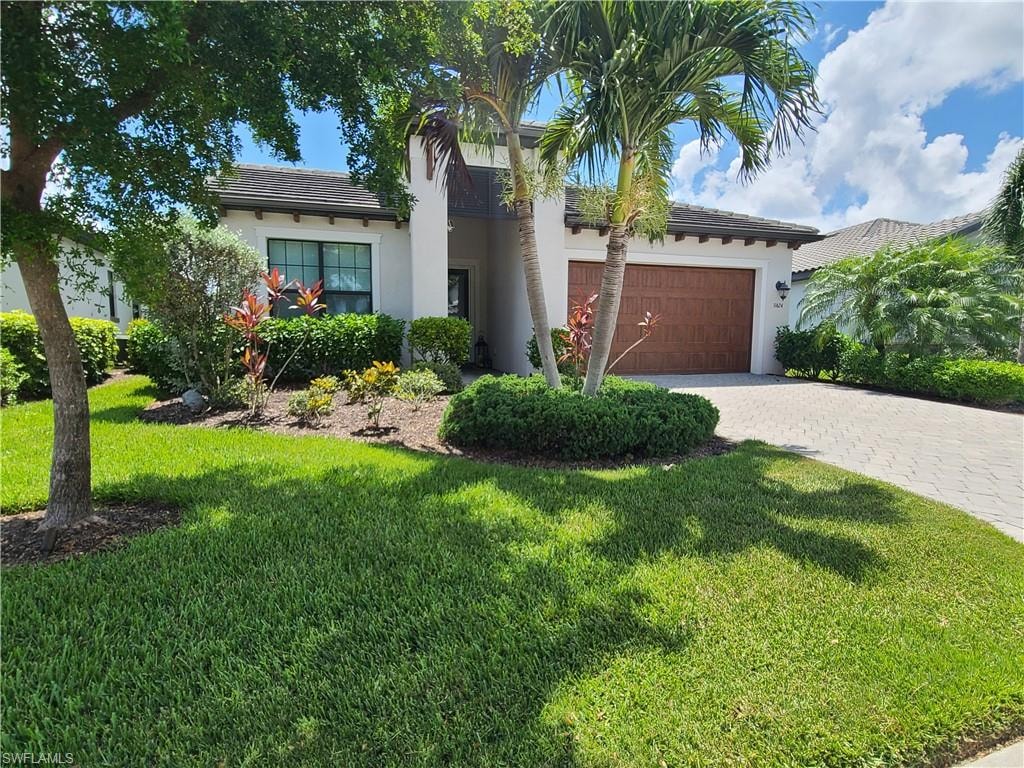 Mediterranean / spanish home with a garage and a front lawn