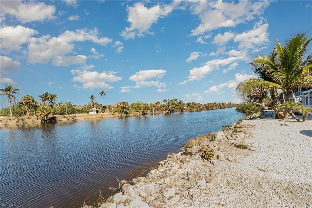 Waterfront property featuring a calm canal, natural rock shoreline, and tropical foliage