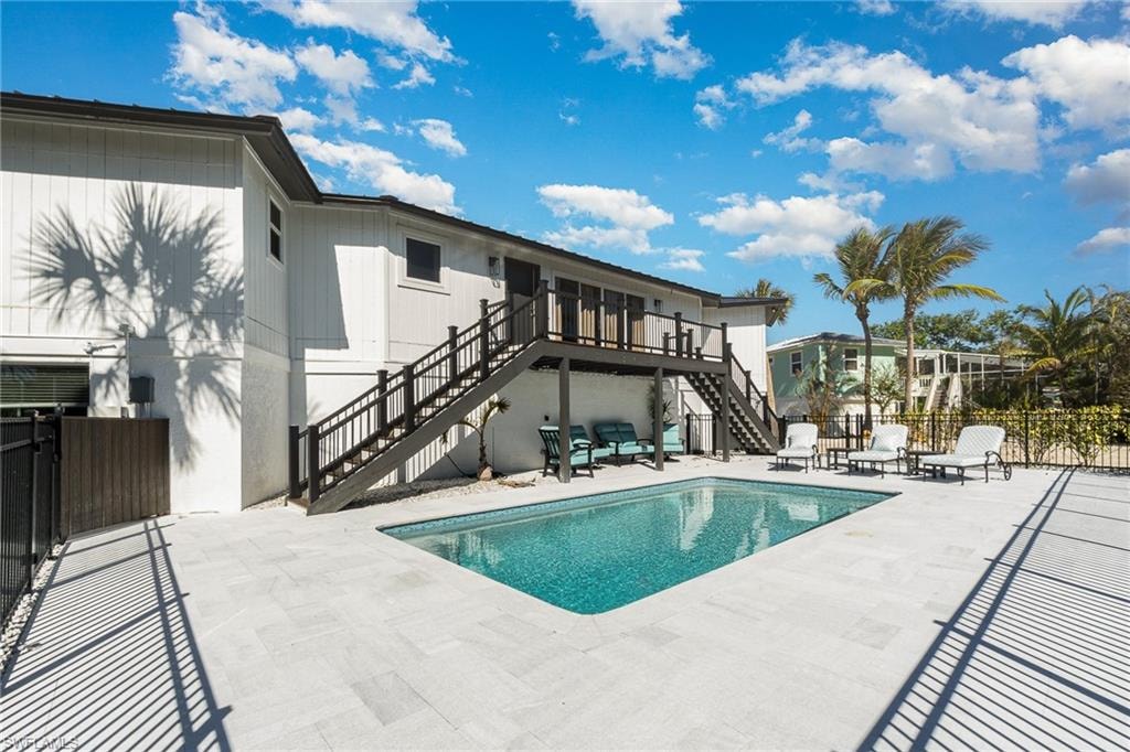 Exterior featuring a rectangular pool with a mosaic tile interior, surrounded by light-toned paver decking