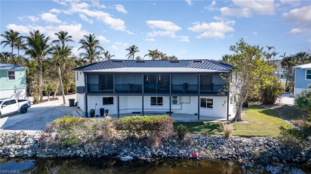 Two-story residence featuring a metal roof and screened upper-level balcony