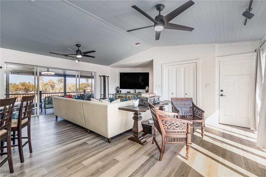 Open-concept living area featuring wood-finish flooring, a light blue beadboard ceiling, and multiple ceiling fans