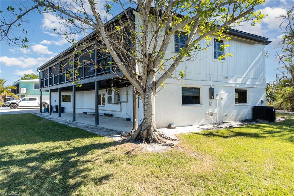 Two-story property featuring a screened upper-level balcony and a covered ground-level patio