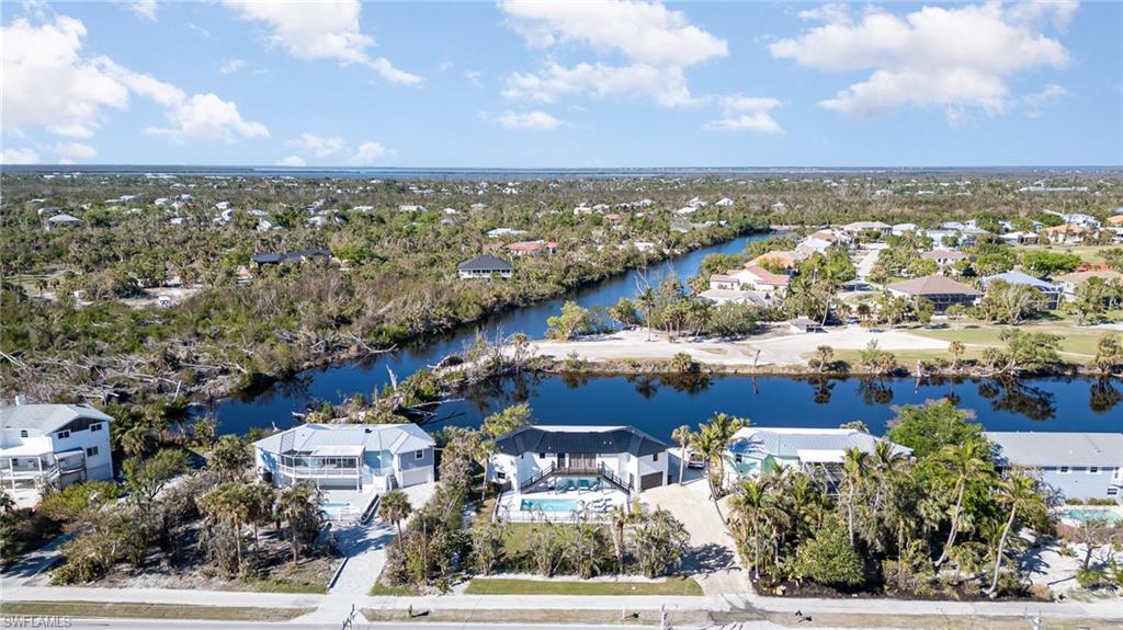 Waterfront property featuring a private boat dock, integrated swimming pool, and mature palm tree landscaping