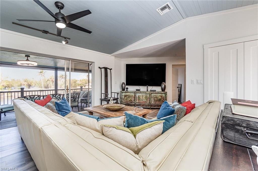 Living area featuring a vaulted tongue-and-groove ceiling, expansive sliding glass doors, contemporary ceiling fan, and recessed lighting