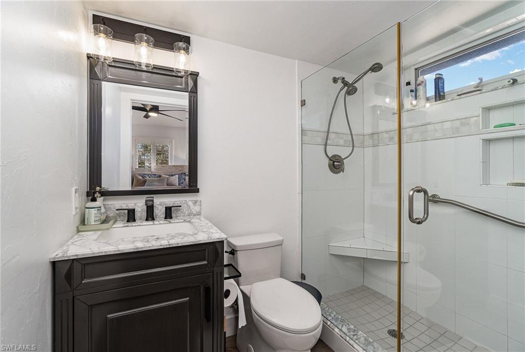 Bathroom featuring a glass-enclosed shower with a built-in bench and a window