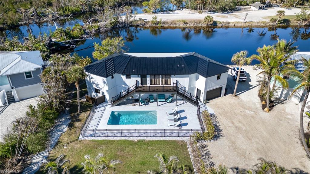 Modern white residence featuring a black metal roof and an integrated swimming pool