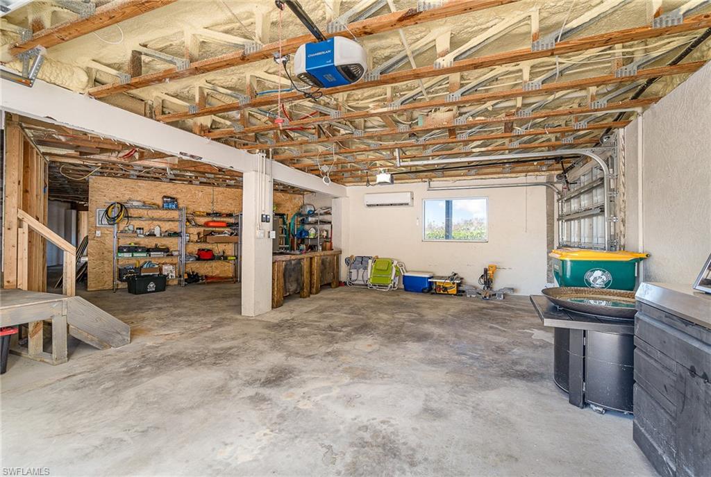 Expansive garage featuring a concrete floor, exposed wood beam ceiling, and a prominent garage door mechanism