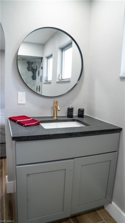 Contemporary vanity featuring a dark countertop, an undermount sink, and a gold-finish faucet
