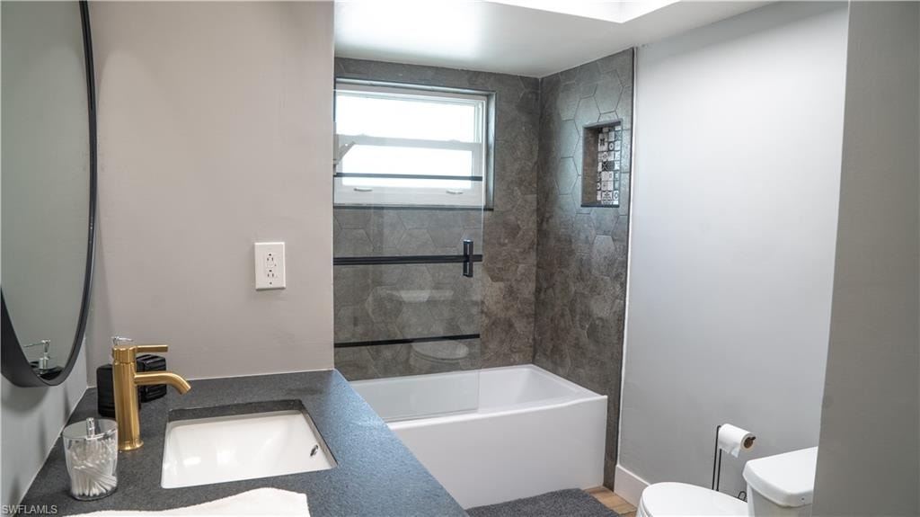 Bathroom featuring a tub/shower combination with hexagonal wall tile, a built-in shower niche, and a window