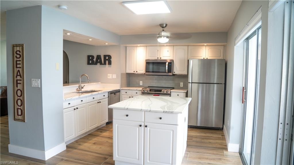 Modern kitchen featuring white cabinetry, stainless steel appliances, and a central island with a stone countertop