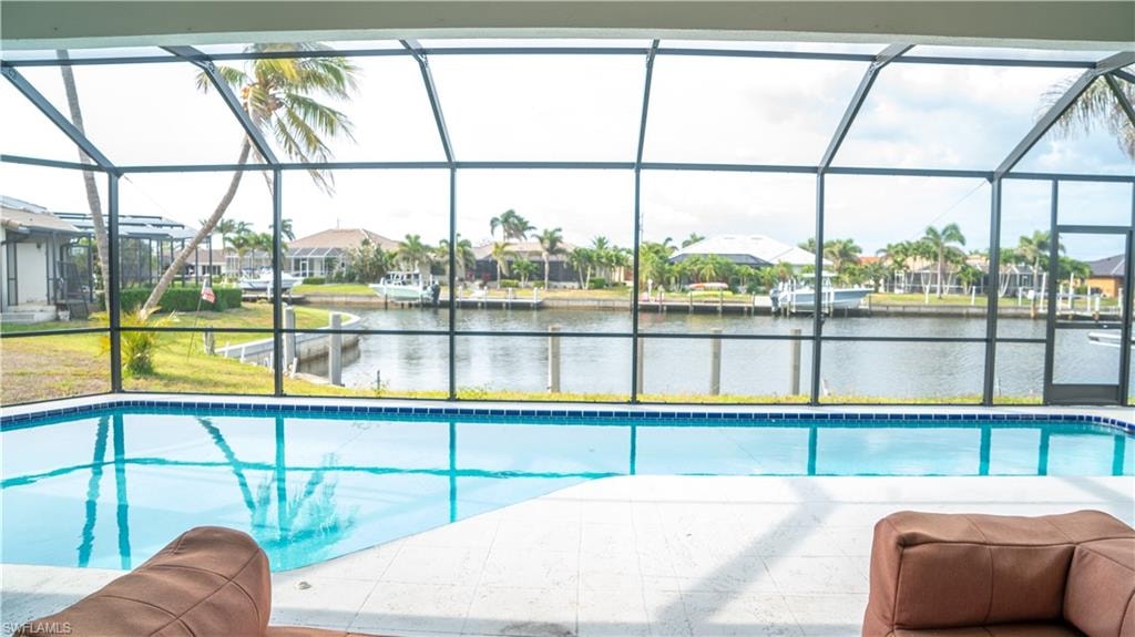 Screened lanai featuring a swimming pool, white tile decking, and waterfront canal access