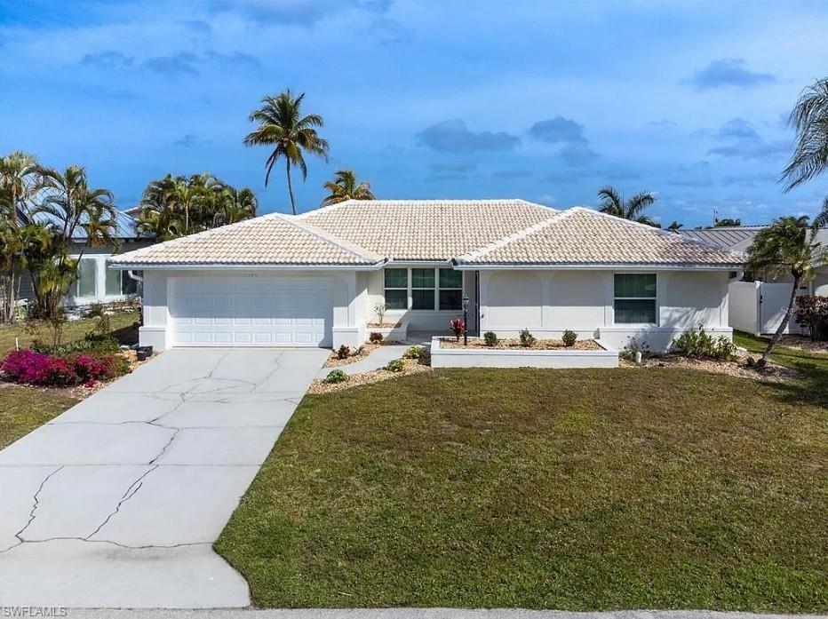 Single-story residence featuring a white exterior, a white tile roof, and a two-car garage