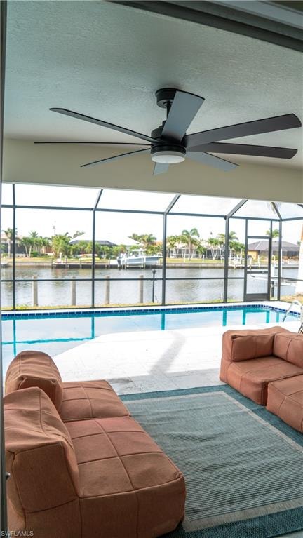 Screened outdoor living area featuring a large ceiling fan with integrated lighting, a concrete pool deck, and a full-size pool with blue tile accents