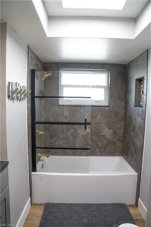 Bathroom featuring a white bathtub with gold-tone fixtures, hexagonal tile surround, and an integrated shower niche