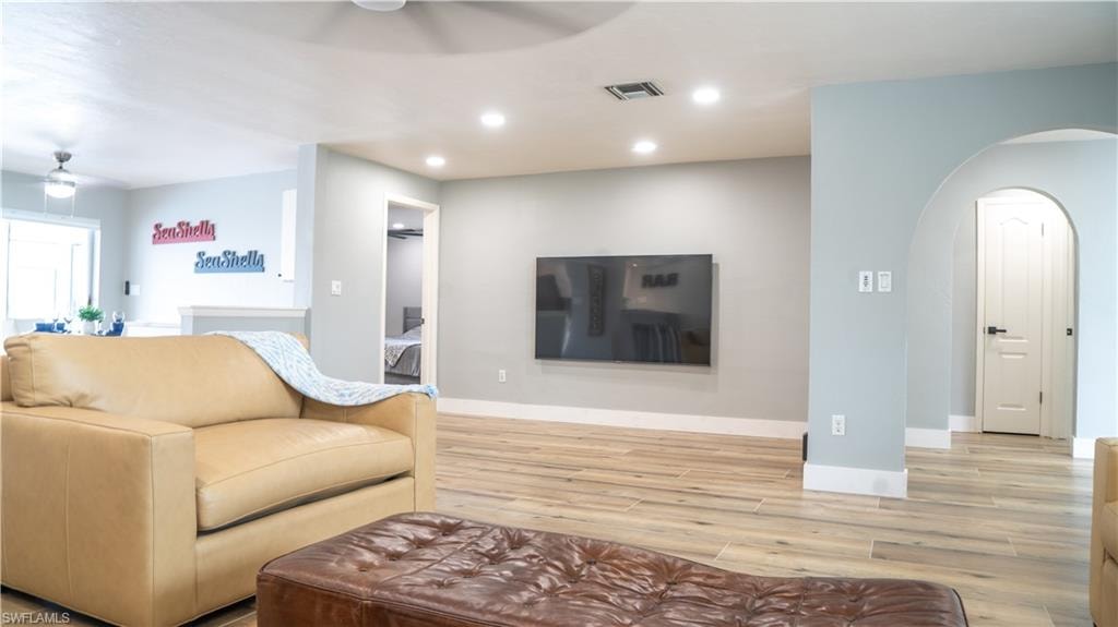 Spacious living area featuring wood-finish flooring, recessed lighting, and an arched doorway