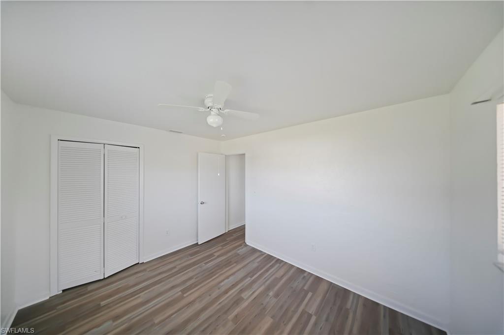 Interior room featuring wood-finish flooring, white walls, and a ceiling fan with integrated lighting