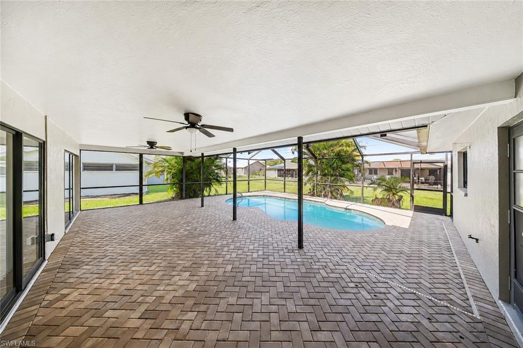 Screened lanai featuring a curved swimming pool and herringbone brick paver flooring