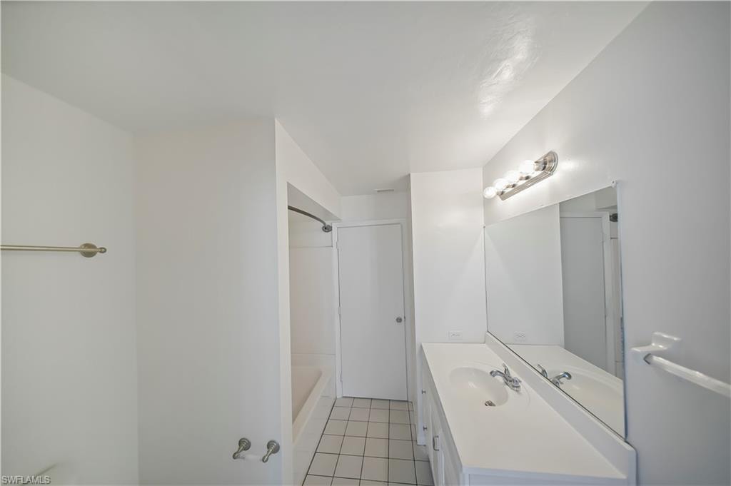 Bright bathroom featuring a vanity with an integrated sink, polished chrome faucet, and a large wall-mounted mirror