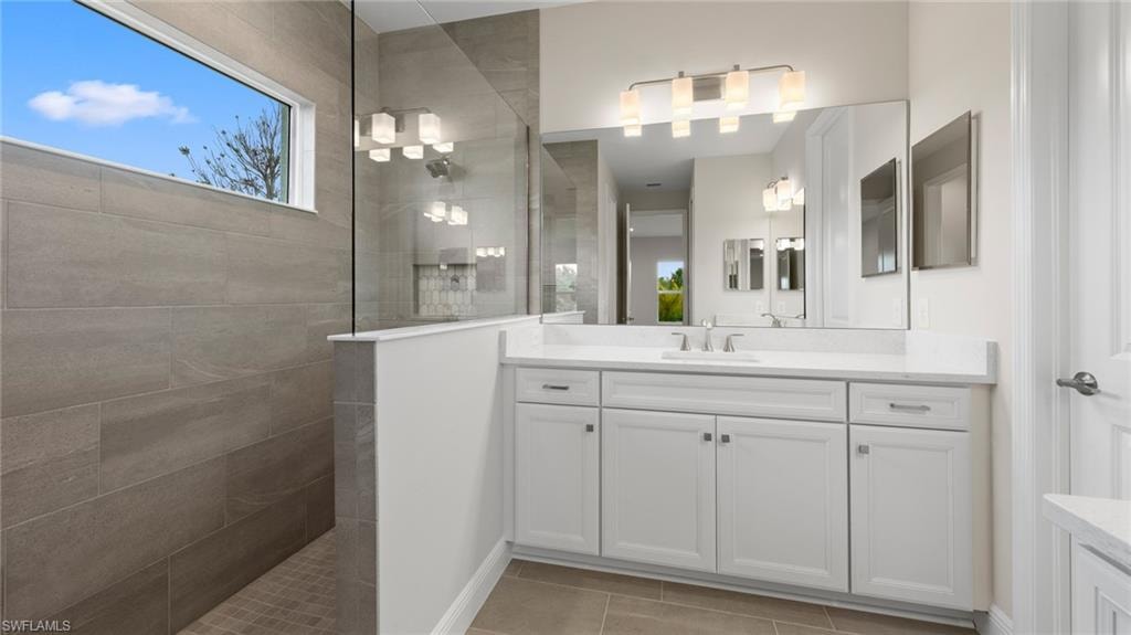 The walk-in shower is wrapped in large-format grey tile to the ceiling with a recessed niche, while a clerestory window bathes the dual-vanity owner's bath in natural light.