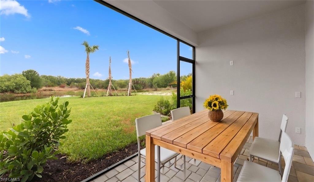 Alfresco dining on the paver-finished lanai overlooks open green space and serene water views, a ceiling-fan-ready covered space for shaded Florida afternoons.