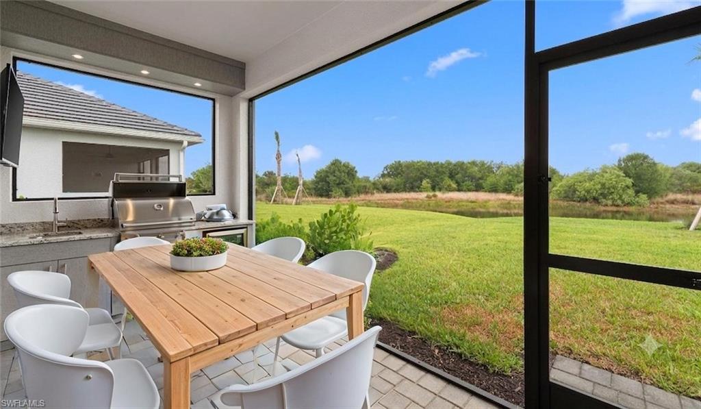 A covered, bronze-screened lanai with a built-in natural-gas outdoor kitchen and Slate paver flooring opens to sweeping preserve views, built for year-round outdoor entertaining.