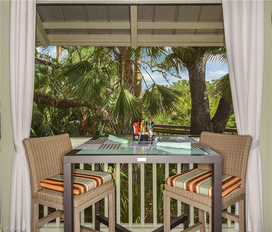 An intimate covered dining nook framed by drapery and lush palm views.