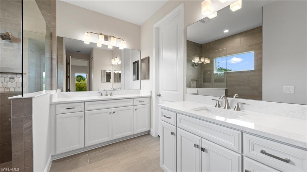 Dual vanities topped with Ashen Grey quartz, white Wentworth cabinetry, and a glass walk-in shower create a refined owner's bath.