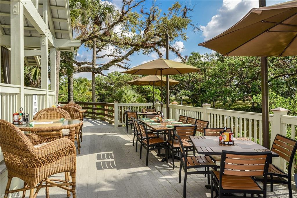 Umbrella-shaded terrace seating beneath moss-draped oaks at the community's riverside restaurant.
