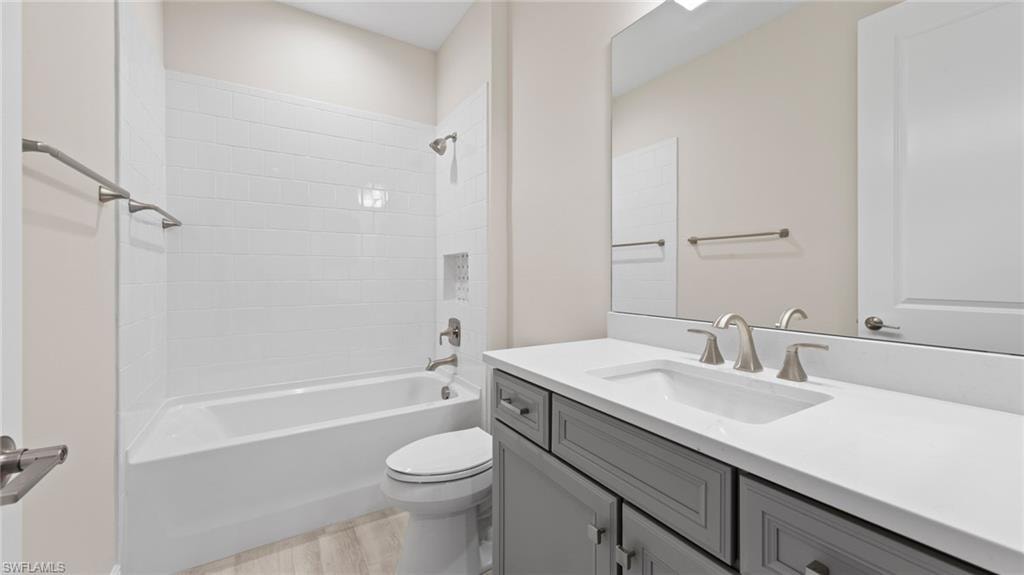 The guest bath pairs a Stone Gray vanity with Ethereal White quartz, a white-tiled tub-shower combination, and brushed-nickel fixtures.