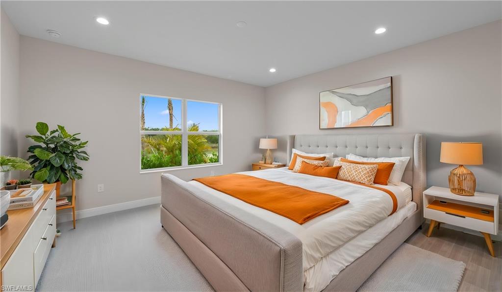 The owner's suite offers plush patterned carpeting, recessed lighting, and oversized impact-glass windows that frame tranquil green views, a restful private retreat.