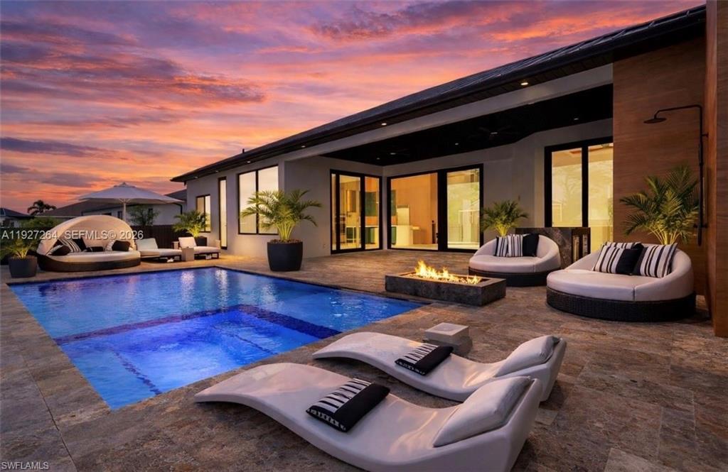 Expansive outdoor living area featuring a rectangular pool with an integrated spa, surrounded by large format tile flooring