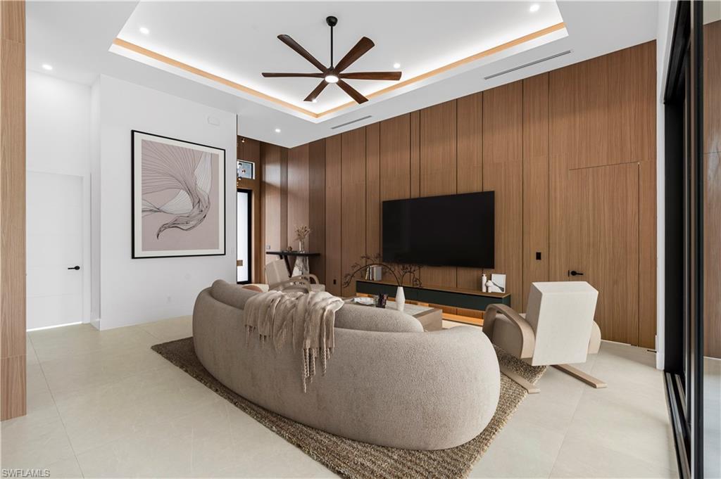 Living area featuring a wood-panel accent wall, recessed lighting, and a ceiling fan