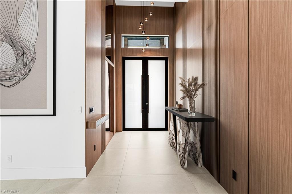 Entryway featuring extensive wood-finish paneling, light-toned tile flooring, and a contemporary pendant light fixture