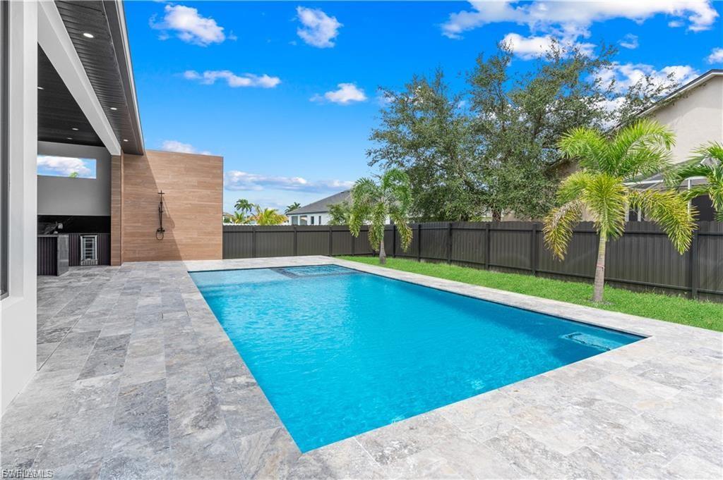 Rectangular swimming pool with integrated spa and light blue interior finish, surrounded by large format gray tile decking