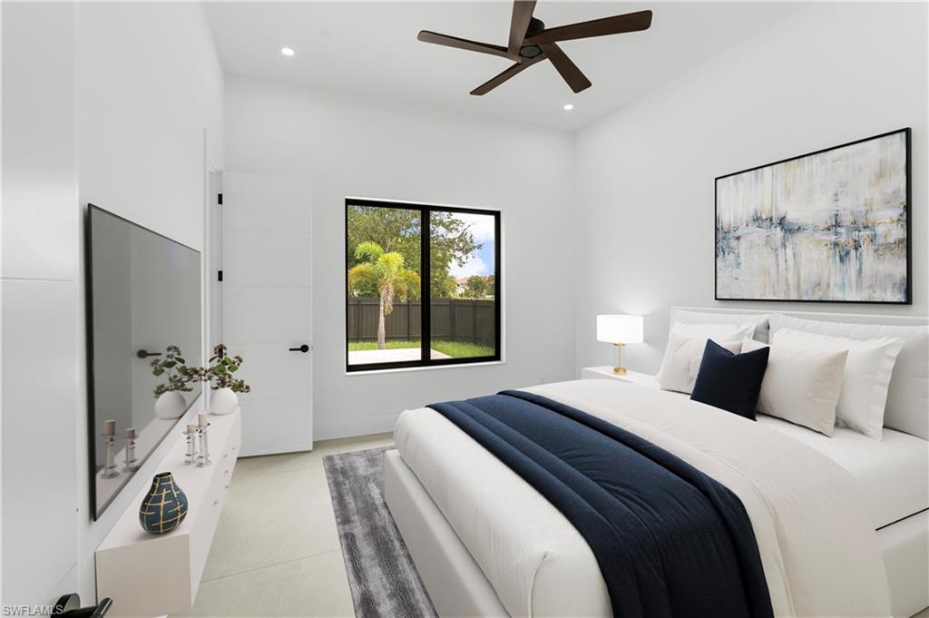 Bedroom featuring a black-framed window, a dark ceiling fan, light-toned flooring, a flat-panel door with black hardware, and an accent wall