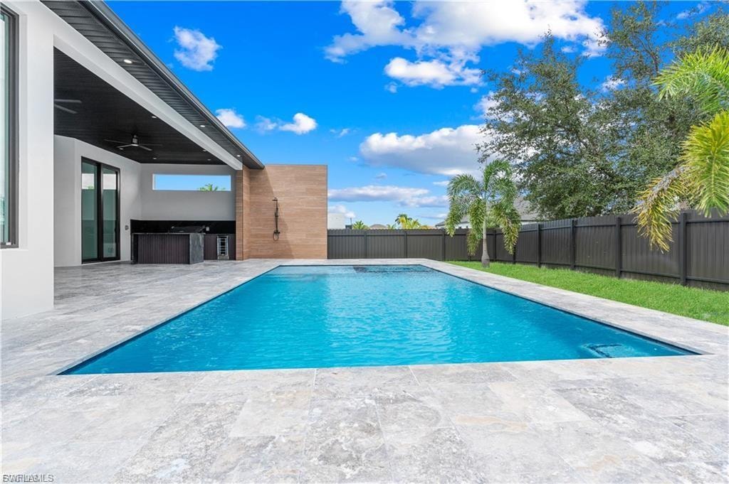 Rectangular swimming pool surrounded by light-toned paver decking