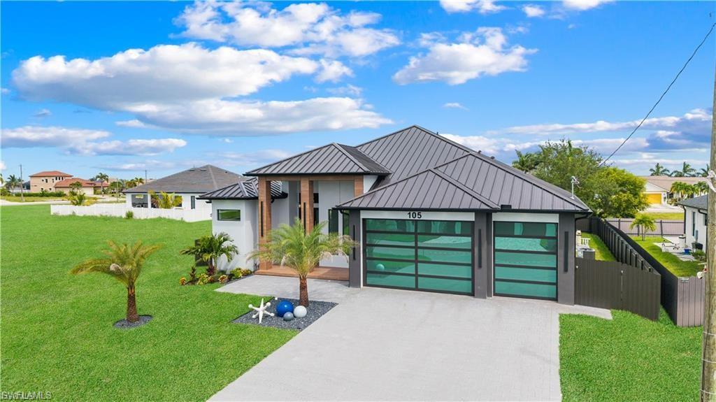 Contemporary residence featuring a metal roof, two modern glass garage doors, and a concrete driveway