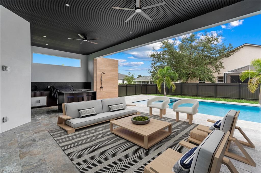 Covered outdoor living space featuring a dark slat ceiling with integrated lighting and ceiling fans