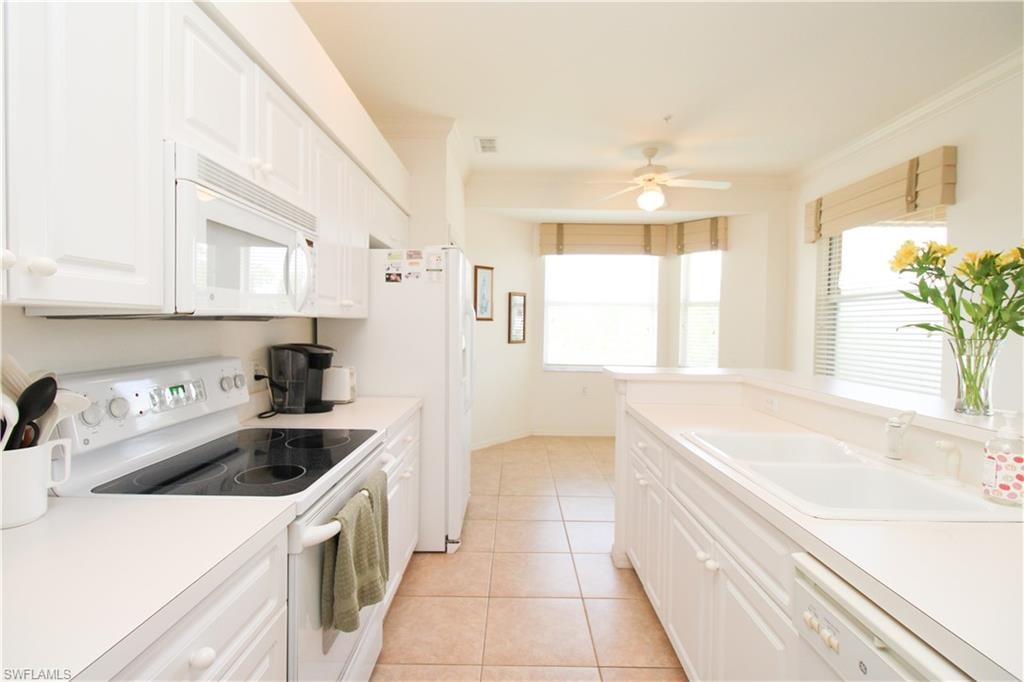 Kitchen featuring light tile patterned flooring, white appliances, white cabinetry, and sink