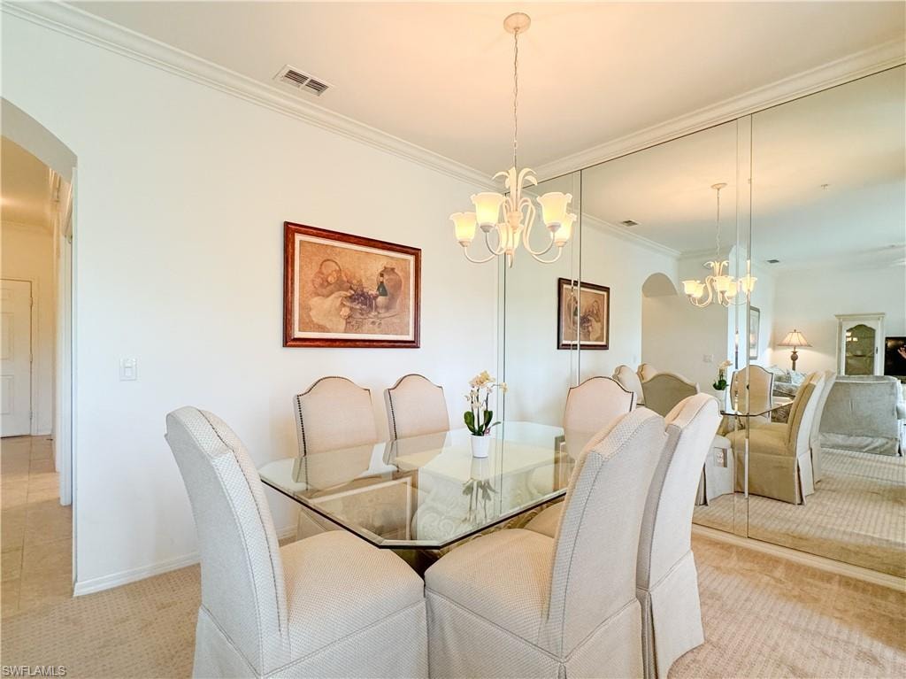 Dining room featuring crown molding, an inviting chandelier, and light colored carpet