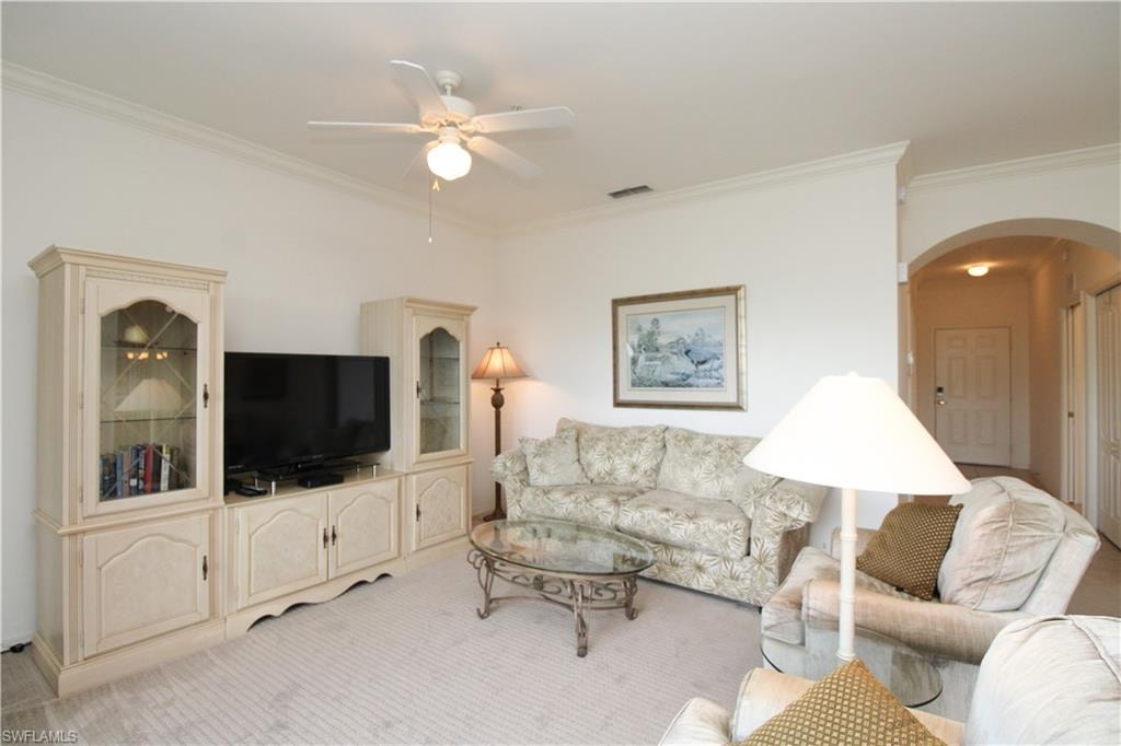 Carpeted living room with ornamental molding and ceiling fan