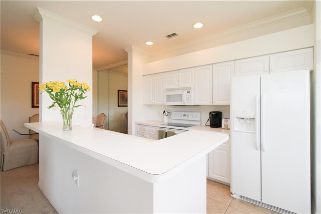 Kitchen featuring white appliances, light tile patterned floors, white cabinetry, and ornamental molding