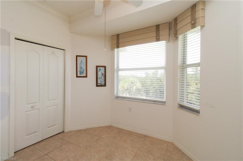 Unfurnished bedroom with multiple windows, light tile patterned floors, ceiling fan, and a closet