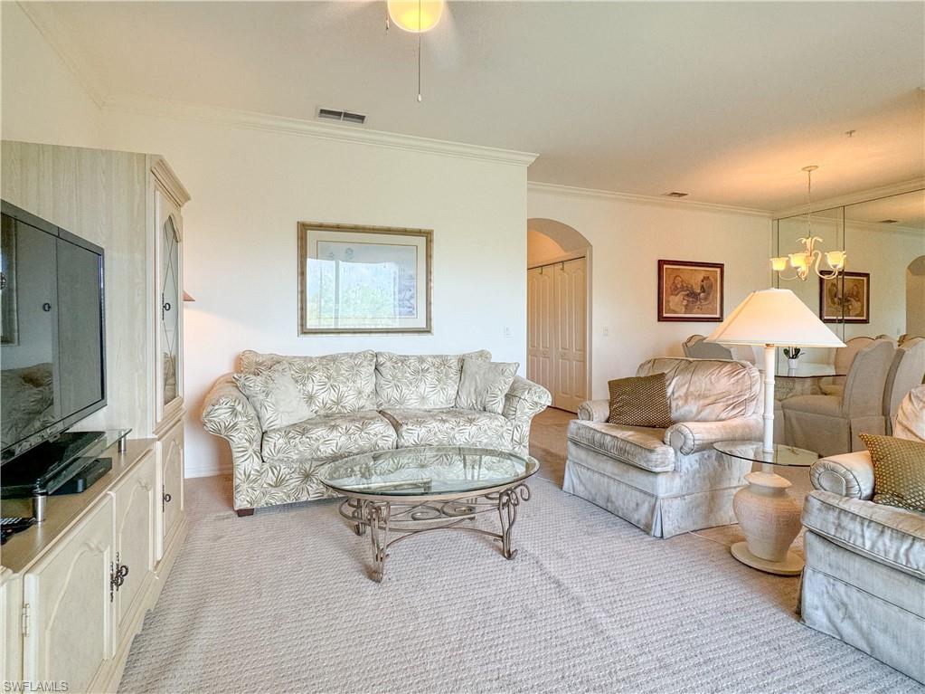 Living room featuring ceiling fan with notable chandelier and crown molding