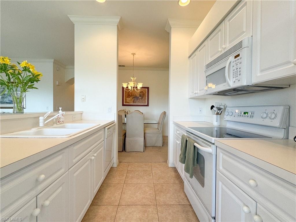 Kitchen with white appliances, a notable chandelier, light tile patterned floors, sink, and white cabinets