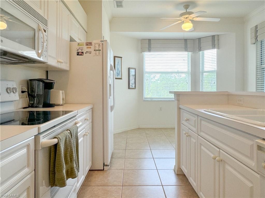 Kitchen with white appliances, white cabinetry, light tile patterned flooring, ceiling fan, and ornamental molding