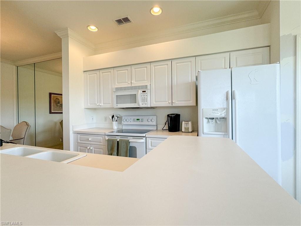 Kitchen featuring ornamental molding, sink, white appliances, and white cabinets