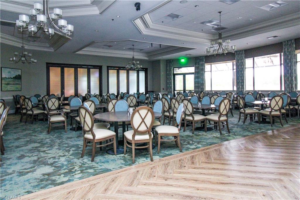 Dining room featuring parquet floors, a raised ceiling, ornamental molding, and an inviting chandelier