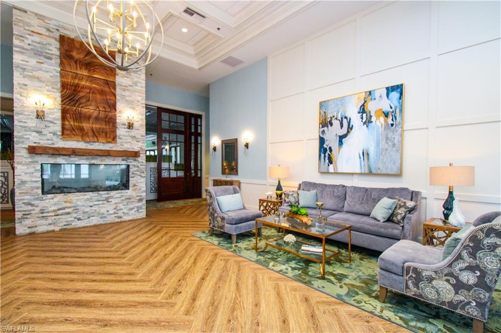 Living room featuring a notable chandelier, parquet flooring, a towering ceiling, and a fireplace